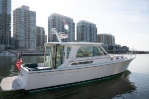 2014 Back Cove 37 cabin cruiser helm station with dual Garmin displays and leather helm chair in pilothouse.