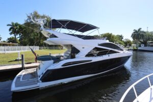 Sunseeker Manhattan 55 salon with cream upholstered seating, teak accents, and large windows overlooking the water.