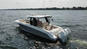 Boston Whaler 350 Realm center console helm with dual Garmin displays, steering wheel, and throttle controls overlooking t...