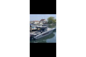 Helm station of 2024 Fountain 38 SC center console with dual Garmin displays, stainless steel wheel, and black upholstered...