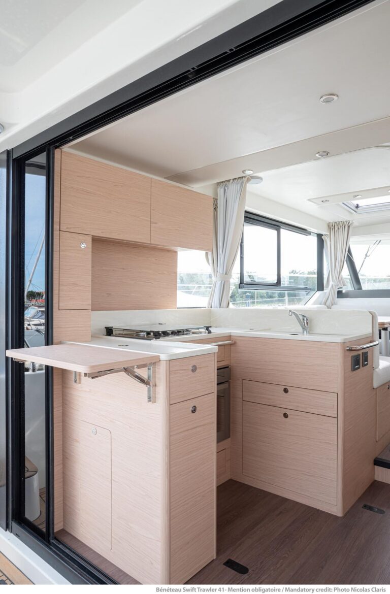 2026 Beneteau Swift Trawler 41 Fly salon with upholstered seating, large windows, and teak accents in South Dartmouth, MA.