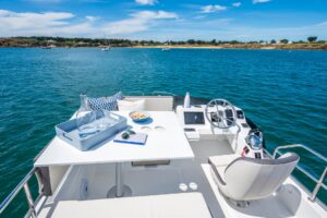2027 Beneteau Antares 11 Fly flybridge helm station with dual helm seats, Garmin electronics, and hardtop canopy overlooki...