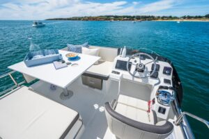 2027 Beneteau Antares 11 Fly flybridge helm station with dual helm seats, steering wheel, and Garmin electronics displays ...