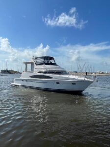 Carver 444 Cockpit Motor Yacht helm station with dual Garmin displays, leather captain's chair, and forward cabin visibili...