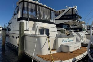 Bow seating and forward cabin entry on 2003 Carver 444 Cockpit Motor Yacht with curved windscreen and teak accents.