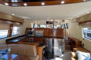 Carver 56 Voyager pilothouse salon with curved settee seating, overhead cabin lighting, and forward visibility through win...
