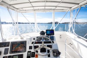 2007 Luhrs 36 Convertible helm station with dual Garmin displays, steering wheel, and throttle controls overlooking the ca...