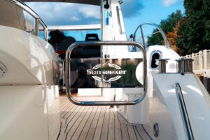 Sunseeker Predator 60 salon with cream upholstered seating, teak flooring, and large windows overlooking the water.