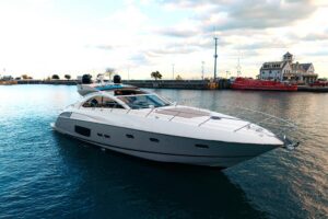 Sunseeker Predator 60 salon with cream upholstered seating, teak flooring, and large windows overlooking the water.