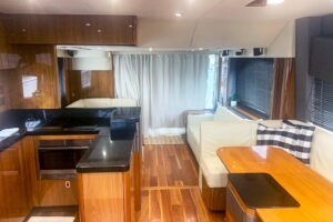 Sunseeker Manhattan 65 salon with cream upholstered seating, teak flooring, and large windows overlooking the water.