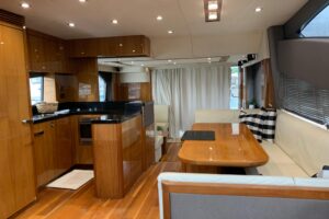 2016 Sunseeker Manhattan 65 salon with cream upholstery, curved seating, entertainment system, and natural light from wind...