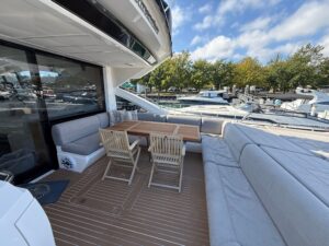 Sunseeker Predator 68 helm station with dual Garmin displays, leather helm chair, and forward windscreen view of cabin ent...