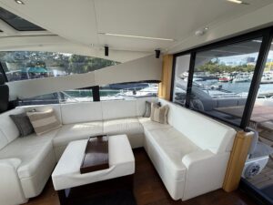Sunseeker Predator 68 salon with cream upholstered seating, entertainment center, and natural light from cabin windows.
