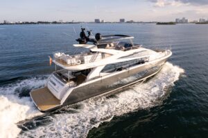 Pearl 80 yacht salon with cream-colored upholstered seating, contemporary lighting fixtures, and panoramic windows overloo...