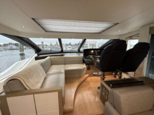 Sunseeker 74 Sport Yacht helm station with dual Garmin displays, leather helm seating, and forward cabin visibility throug...