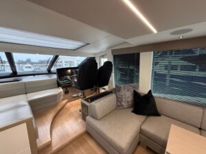 Sunseeker 74 Sport Yacht helm station with dual Garmin multifunction displays, leather helm seat, and teak accents in the ...