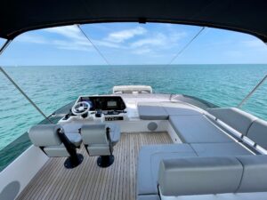 Sunseeker 74 Sport Yacht helm station with dual Garmin displays, leather helm chair, and forward cabin visibility through ...