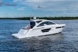 2022 Cruisers Yachts 54 Cantius salon with cream upholstered seating, teak accents, and large windows providing natural li...