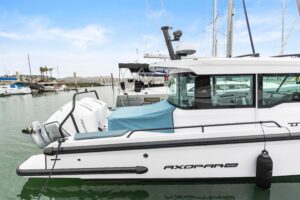 Axopar 37 XC Cross Cabin helm station with dual Garmin displays, leather helm seat, and forward cabin visibility through w...