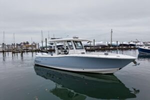 2025 Robalo R300 center console fishing boat with gray hull and hardtop, viewed from starboard profile showing full length...