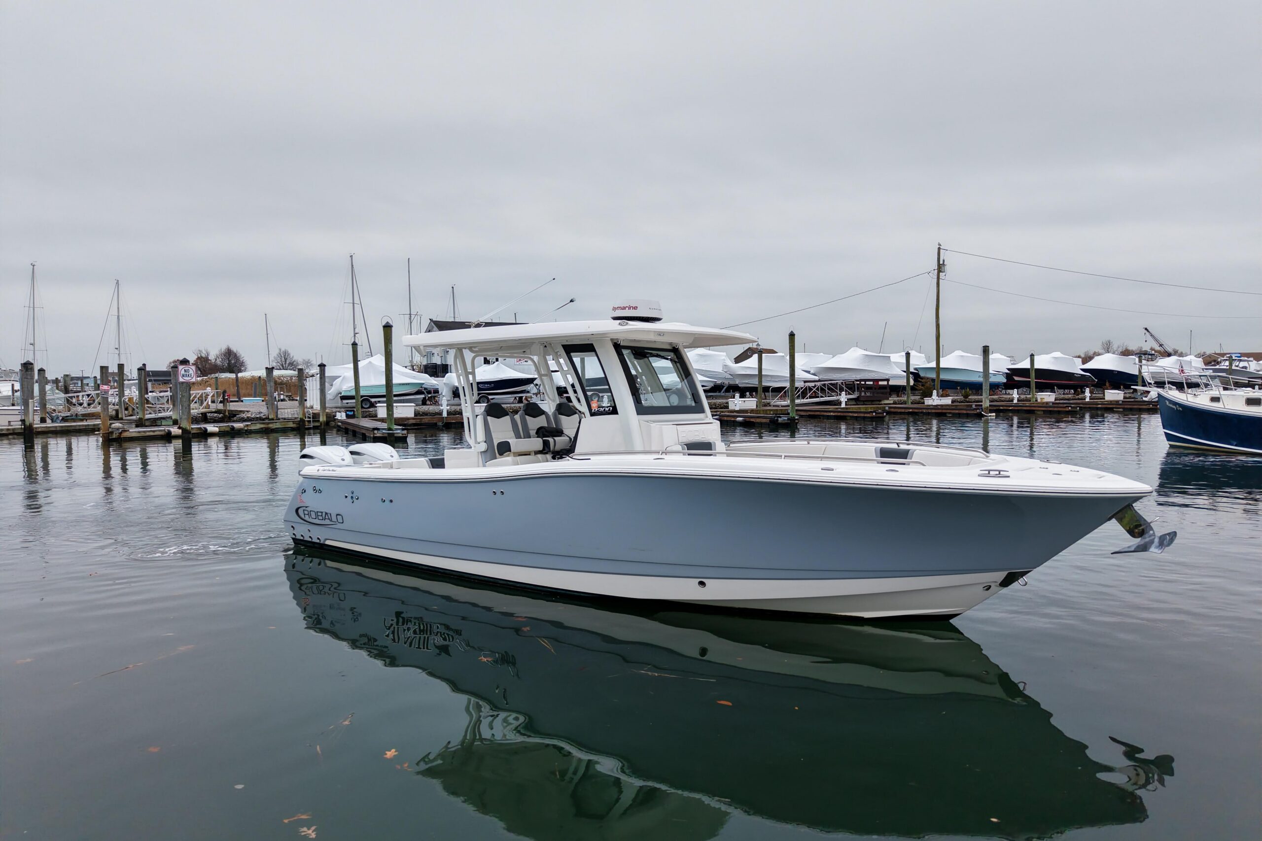 2025 Robalo R300 center console fishing boat with gray hull and hardtop, viewed from starboard profile showing full length...