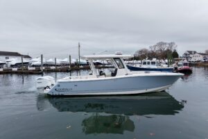Robalo R300 center console helm station with dual Garmin displays, steering wheel, and throttle controls overlooking the bow.