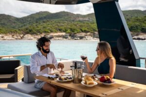 2026 Beneteau Grand Trawler 63 salon with upholstered seating, large windows, and teak accents.