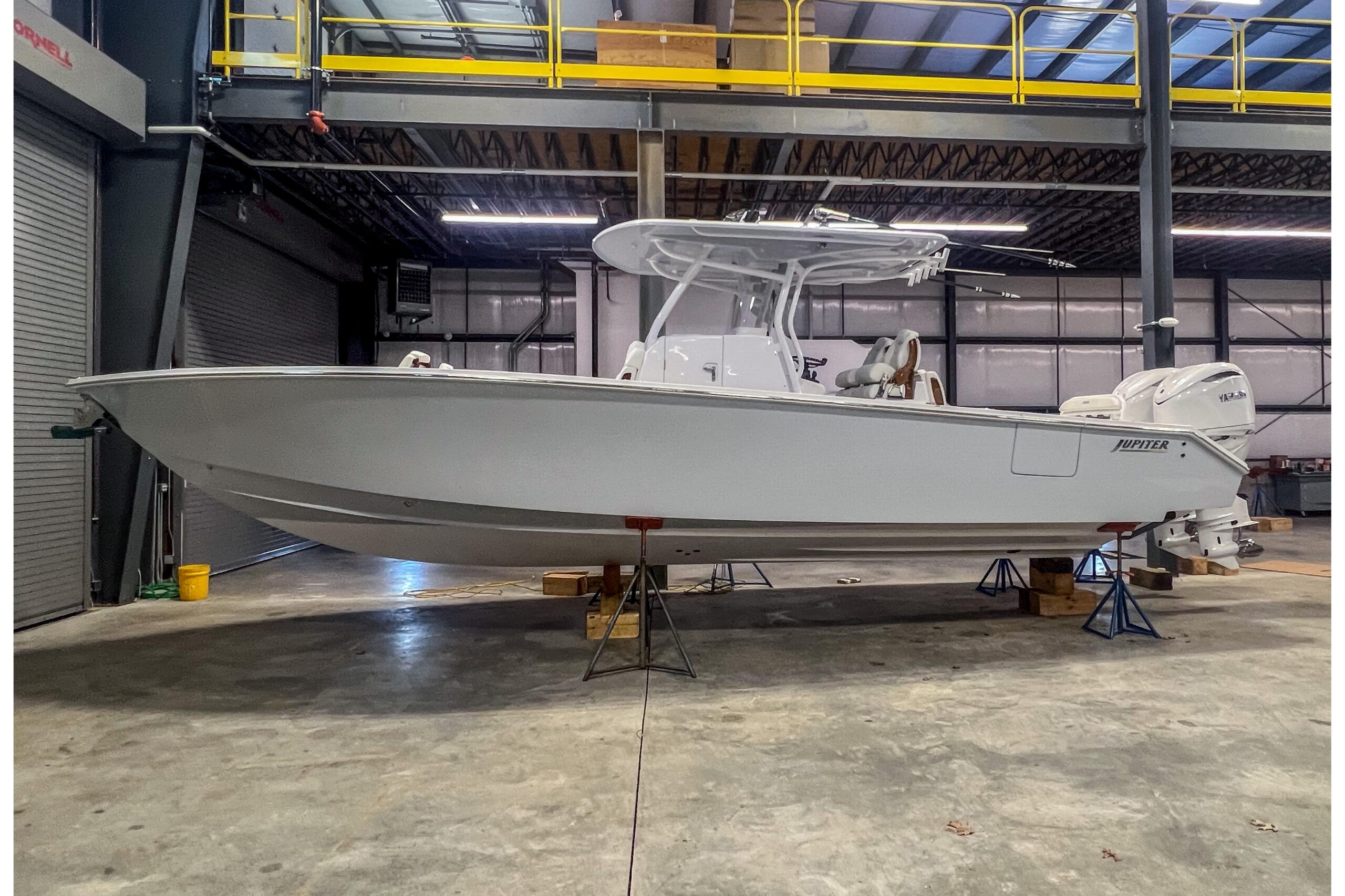 2026 Jupiter 32 center console fishing boat with hardtop and outboard engines shown in profile on the water.