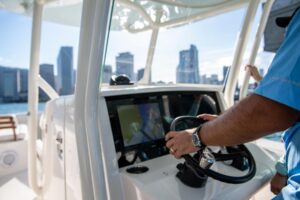 Helm station of 2026 Jupiter 32 center console with dual Garmin displays, steering wheel, and helm seating under hardtop.