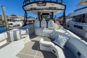Wellcraft 38 T-Top center console helm station with dual Garmin displays, stainless steel wheel, and overhead hardtop canopy.